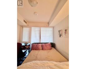 A bedroom with a bed, desk, and window.
