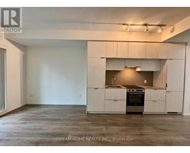 A large, empty room with a kitchen area in the background.
