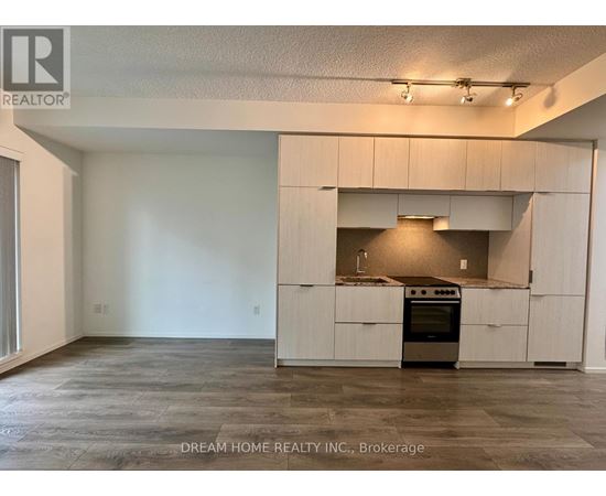 A large, empty room with a kitchen area in the background.