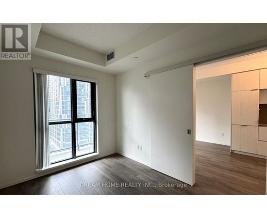 A room with a large window and wooden flooring.