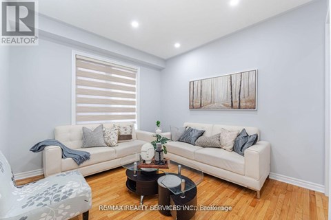 A living room with a white couch and a painting on the wall.