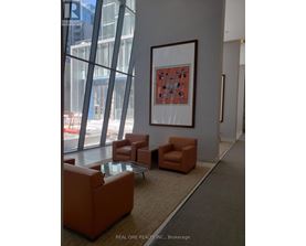 A large framed picture hangs on a wall above a table and chairs in a room.