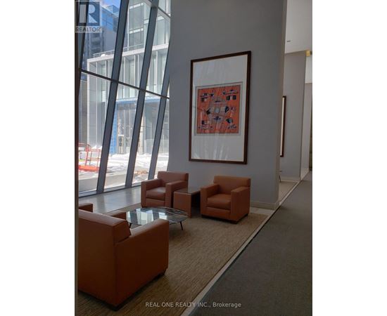 A large framed picture hangs on a wall above a table and chairs in a room.