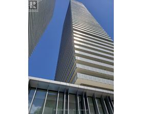A tall building with a glass facade stands next to a shorter building with a striped facade.