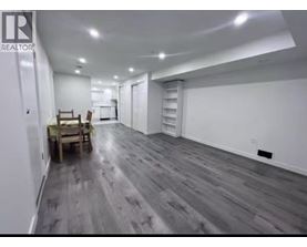 A spacious room with wooden flooring and white walls.