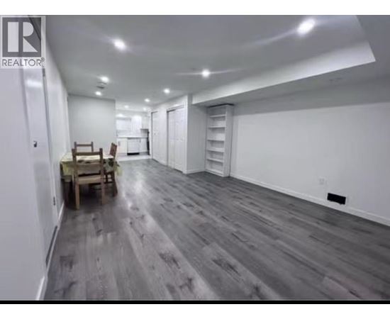 A spacious room with wooden flooring and white walls.
