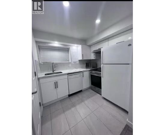 A white kitchen with tile flooring and white appliances.