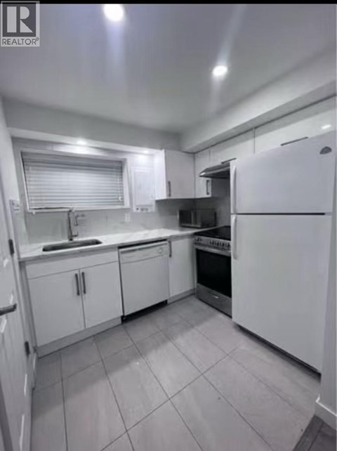 A white kitchen with tile flooring and white appliances.