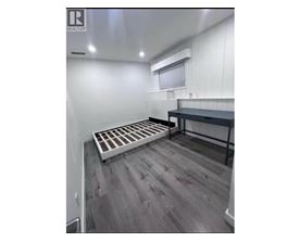 A room with a grey floor and a white wall with a window.