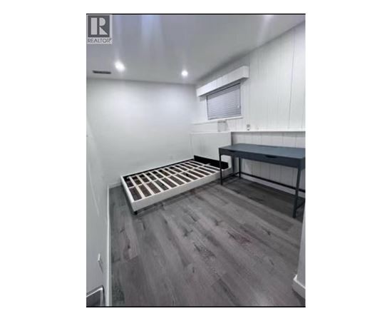 A room with a grey floor and a white wall with a window.