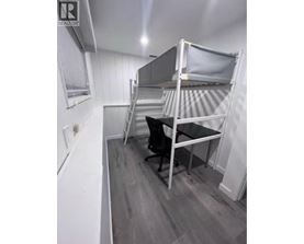 A small room with a bunk bed and a desk.