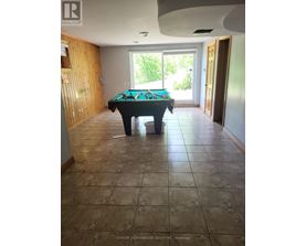 A pool table in a room with tile flooring and a doorway leading to a balcony.