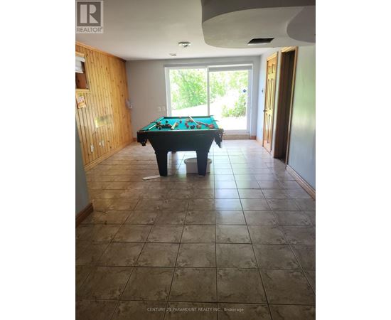 A pool table in a room with tile flooring and a doorway leading to a balcony.