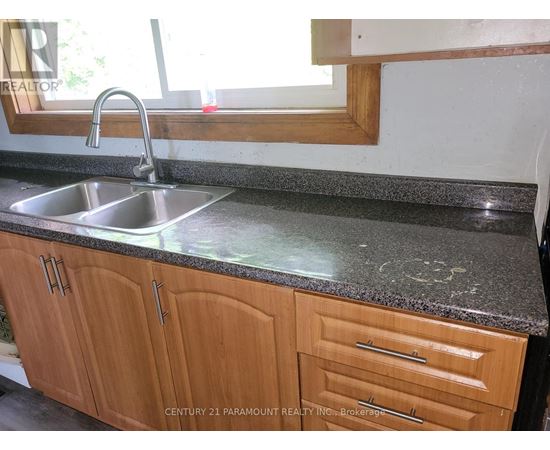 A kitchen counter with a sink and wooden cabinets.