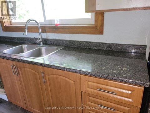 A kitchen counter with a sink and wooden cabinets.