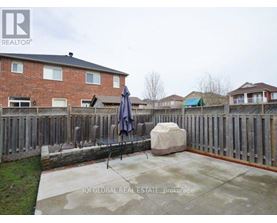 A backyard with a patio, a fence, and a large rock.