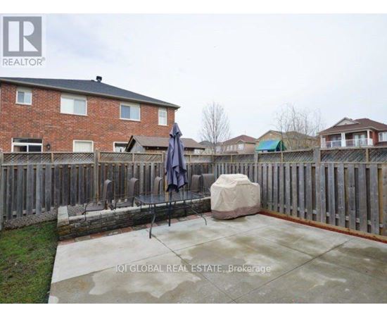 A backyard with a patio, a fence, and a large rock.