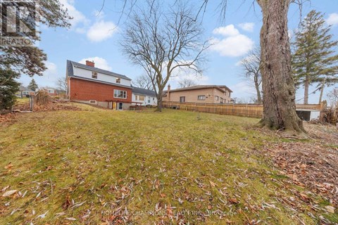 A house with a red brick chimney is surrounded by a grassy field with fallen leaves.