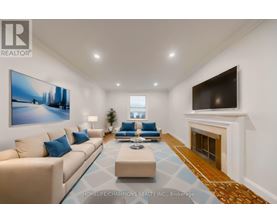 A living room with a beige couch, a blue cushion, a coffee table, a fireplace, and a painting on the wall.