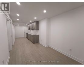 A spacious room with wooden flooring and white walls.