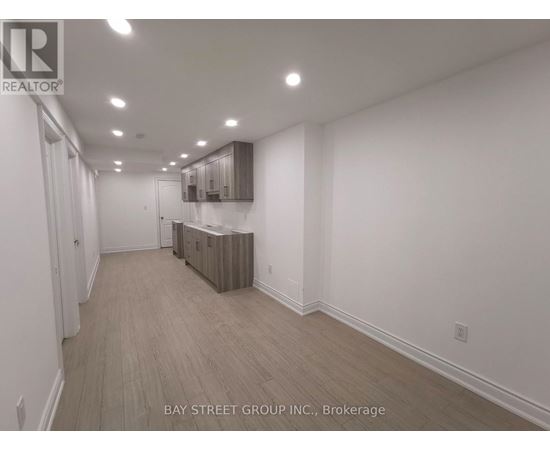 A spacious room with wooden flooring and white walls.