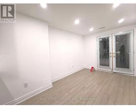 A room with a white wall and a wooden floor with a door on the right side.