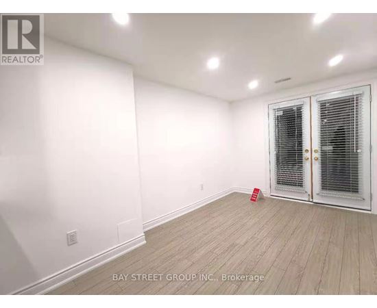 A room with a white wall and a wooden floor with a door on the right side.