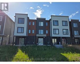 A row of modern townhouses with a grassy area in front.