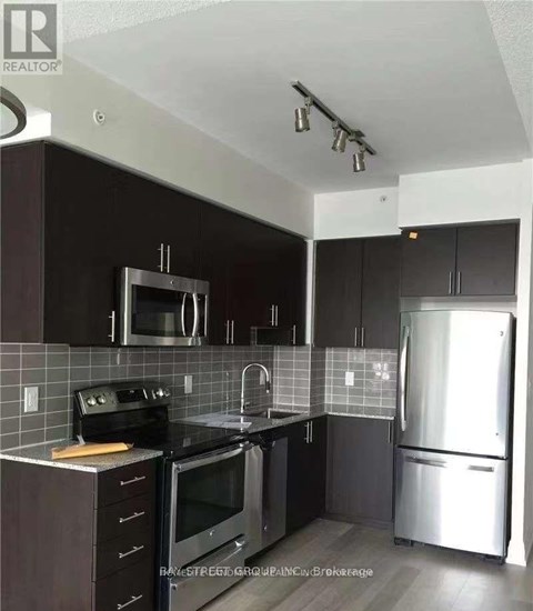 A kitchen with a black counter top and stainless steel appliances.