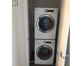 Two washing machines are stacked in a small cabinet.
