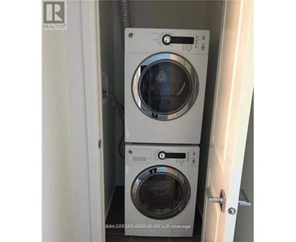 Two washing machines are stacked in a small cabinet.