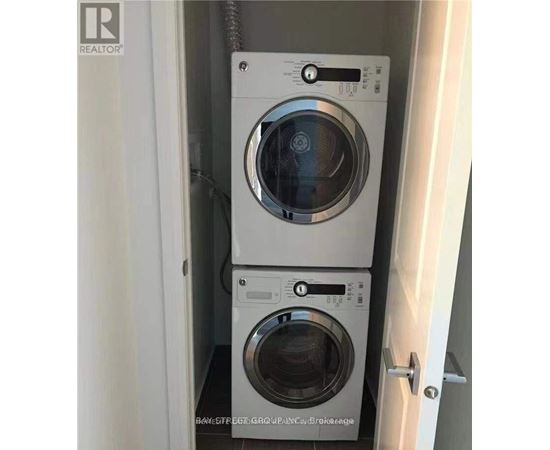 Two washing machines are stacked in a small cabinet.
