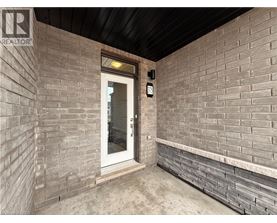 A door with a glass window is in a room with brick walls.