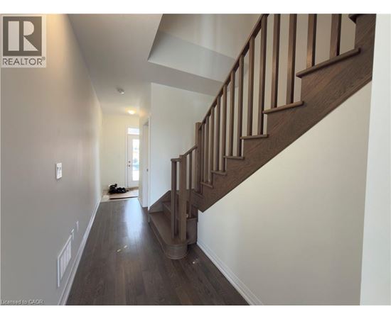 A hallway with a staircase and a pair of shoes on the floor.