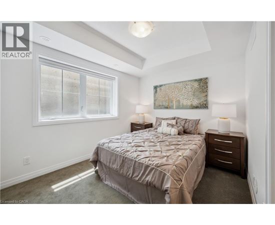 A bedroom with a bed, nightstands, and a window.