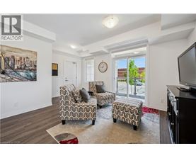 A living room with a couch, chair, ottoman, and a painting on the wall.