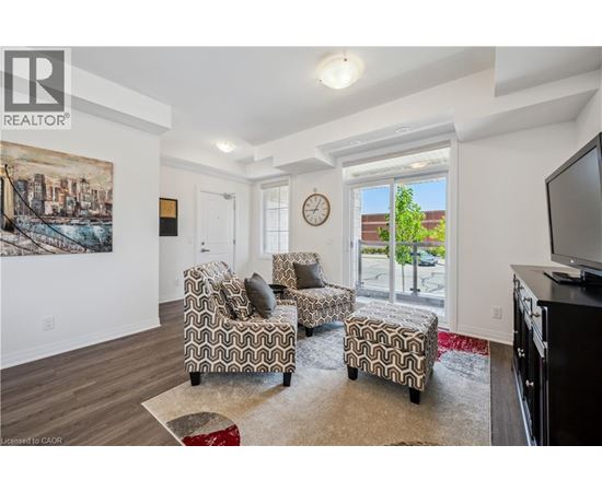 A living room with a couch, chair, ottoman, and a painting on the wall.