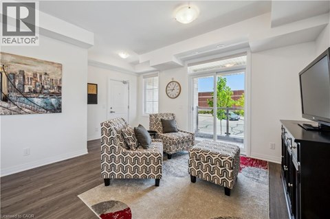 A living room with a couch, chair, ottoman, and a painting on the wall.
