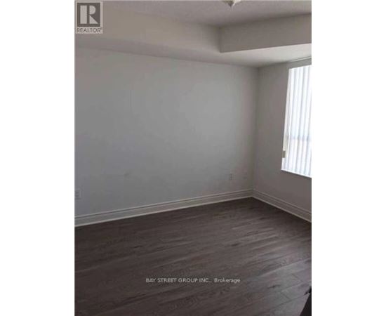 A room with a wooden floor and a window with blinds.