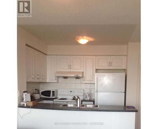 A kitchen with white cabinets and a white fridge.