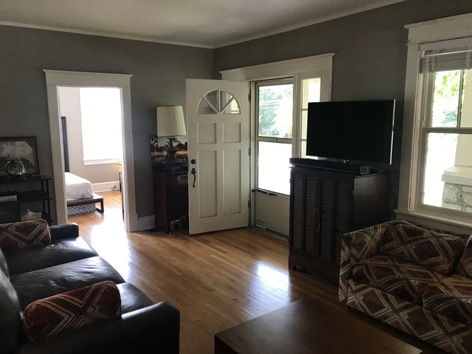 A living room with a black couch and a television.