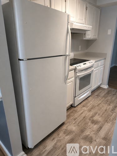 A white refrigerator in a kitchen with wooden cabinets.