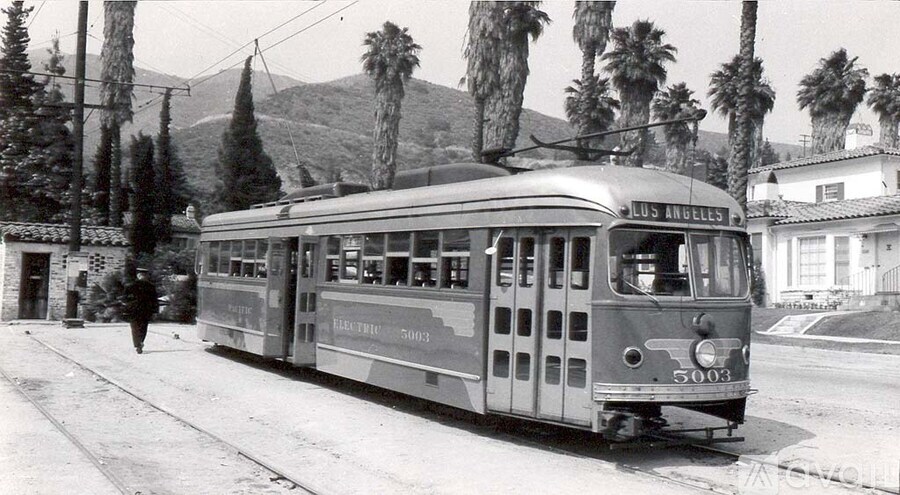 A black and white photo of an old trolley car on a street.