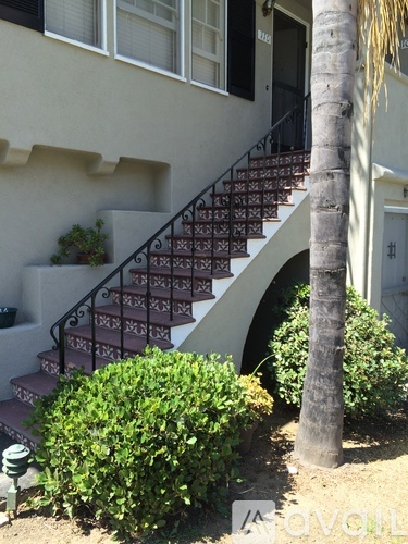 A house with a staircase and a tree in front.