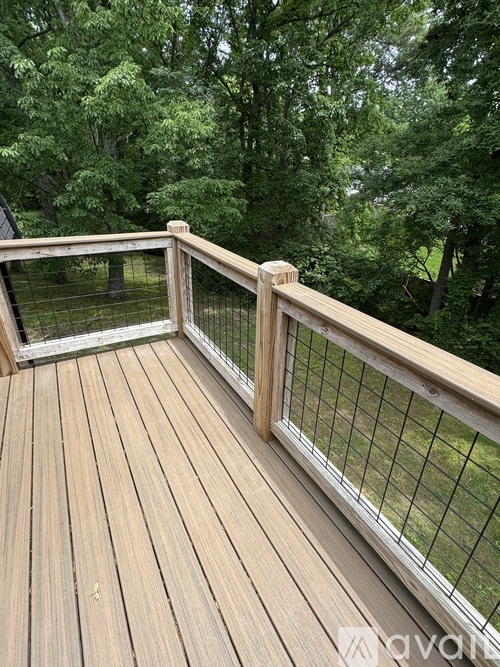A wooden deck with a railing and a mesh screen door.