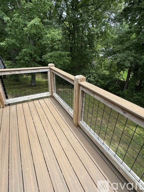 A wooden deck with a railing and a mesh screen door.