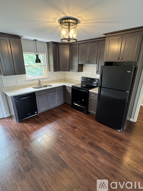 A kitchen with dark wood cabinets and a black fridge.