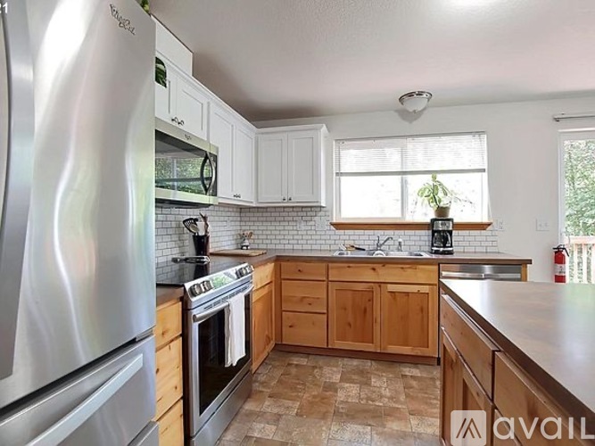 A kitchen with a stainless steel refrigerator, wooden cabinets, and a tiled backsplash.