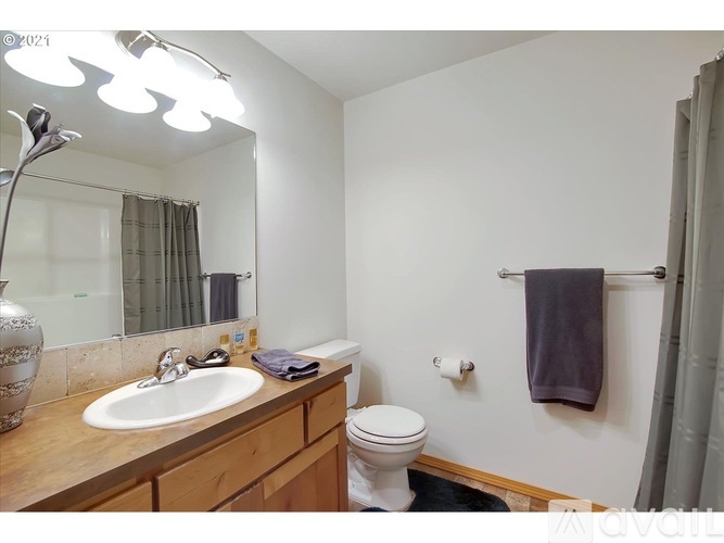 A bathroom with a toilet, sink, mirror, and a towel hanging on the wall.