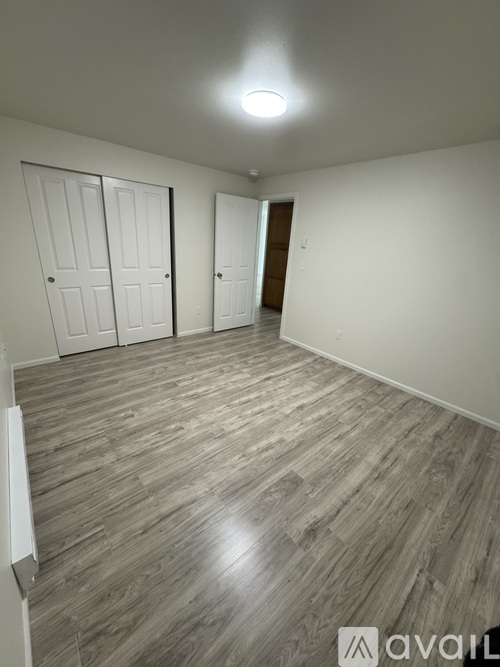 A room with wooden flooring and white walls.